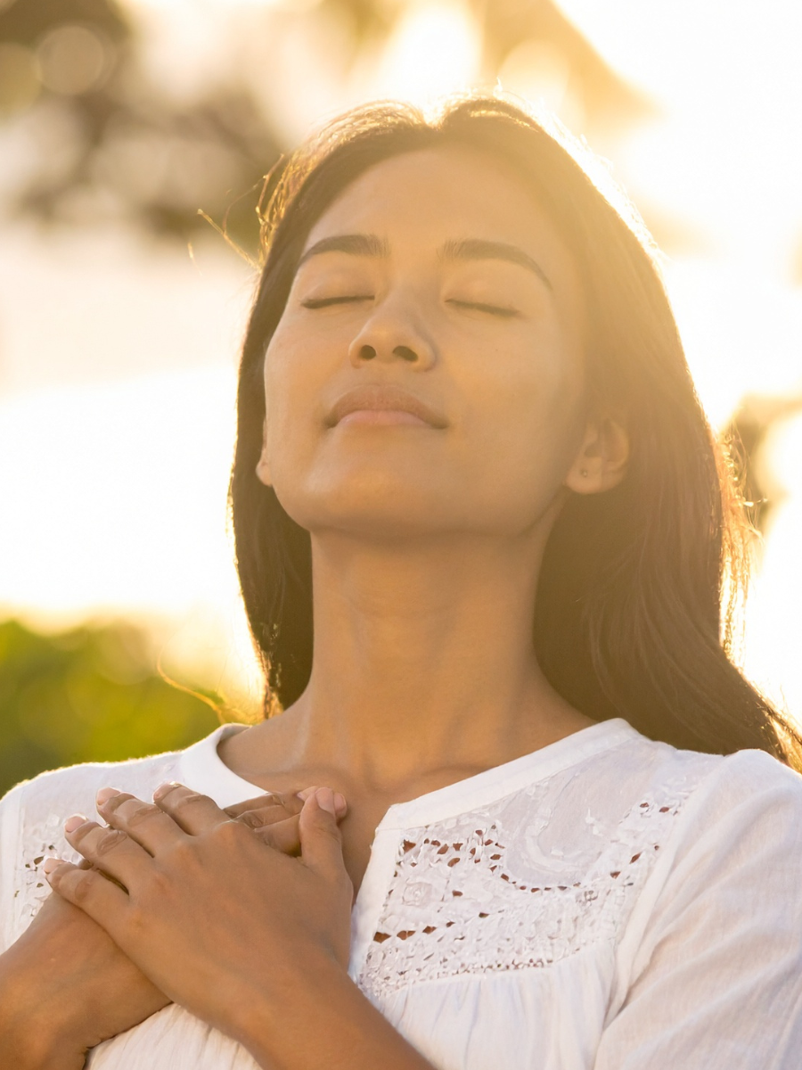 woman meditating with hands placed on her heart